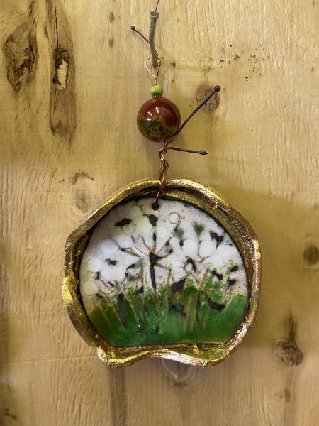 A photograph of a piece of decorative enamel work against a wooden backdrop.